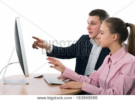 Young Business People Man and Woman discussing Subject sitting at Table in front of modern Desktop pointing on Screen smart casual Clothing white Bacgkround