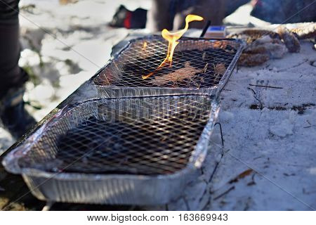 Aluminum disposable (throwaway) outdoor grill used in winter as a temperature contrast between hot grill grid and freezing snow during the December cookout