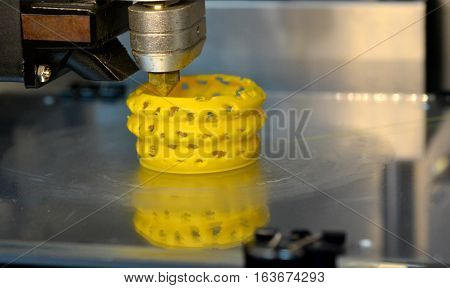 3D printer prints yellow form figure close. Automatic three dimensional 3d printer performs plastic modeling in laboratory. Plastic Wire Filament on 3D Printer. Modern printing technology.