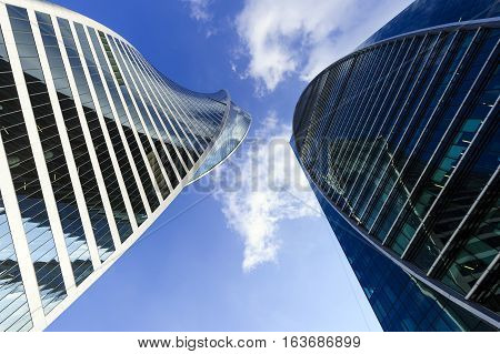 Modern business office skyscrapers, looking up at high-rise buildings in commercial district, architecture raising to the blue sky with white clouds, bottom view