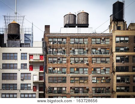 Old vintage apartment buildings with wall of windows and water towers on the roof tops in downtown New York City