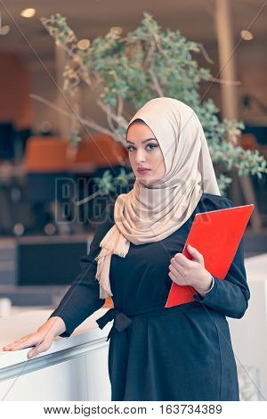 Arabian business woman holding a folder and talking on the phone isolated on white