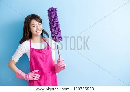 beauty housewife take feather duster and smile to you isolated on blue background asian