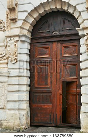 Open free path mystery peeping invitation concept. Old medieval style broun wooden door on classic facade building in Lviv Ukraine