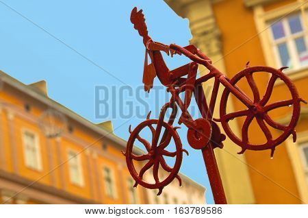 Good news information progress concept. Metal figure of postman with a red bag going up riding bike and delivering mail and newspapers. A man on his bicycle at bright sunny day. part of bicycle repair station