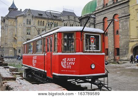 UKRAINE LVIV - DECEMBER 27 2016: Lviv red tram which is a touristic shop to buy different souvenirs. red coffee shop on historical buildings background