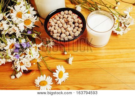 Simply stylish wooden kitchen with bottle of milk and glass on table, summer flowers camomile, healthy foog moring concept noone