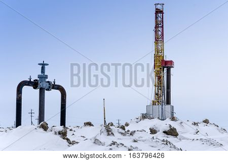 Oil rig and wellhead in the oilfiled during winter time. Oil and gas concept.