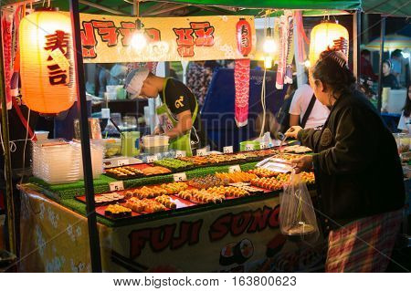 LOEI THAILAND - DECEMBER 31 : Unidentified woman making choice at Sushi stall with seafood at night market on December 31 2016.