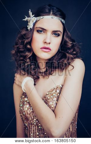 Fashion photo of beautiful girl wearing sparkling evening dress. Professional make-up and hairstyle. Perfect skin. Fashion photo. Gatsby style.