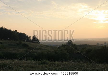 Buitiful cloudy sunset above a village far from city