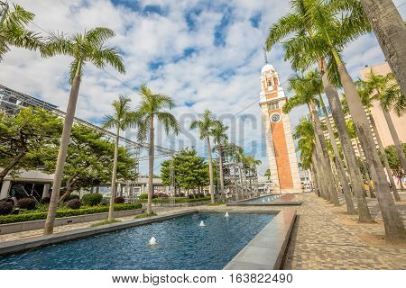 Beautiful view of old Clock Tower with a pool and palm trees at in Tsim Sha Tsui, Kowloon, near Victoria Harbour, Hong Kong.