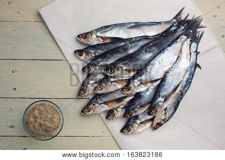 Raw salty sabrefish and salt with spices. Preparation before drying on a rustic wooden table