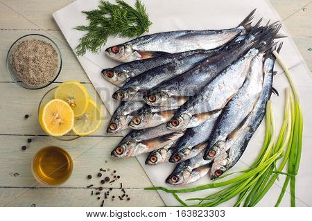 Raw sabrefish slices of lemon herbs oil and spices. Preparation before cooking on a rustic wooden table