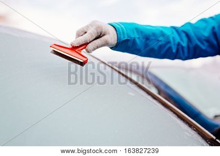 Woman Deicing Front Car Windshield With Scraper