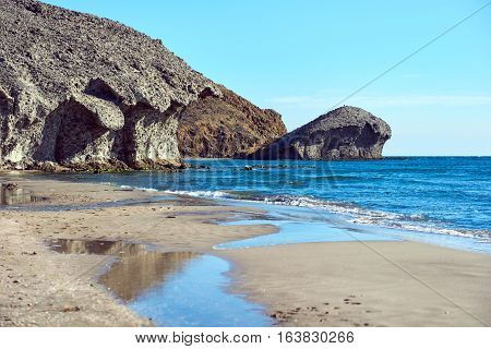 Volcanic rock-formations and crystal clear water at Playa de Monsul. Famous beach in the Cabo de Gata-Nijar Natural Park. Province of Almeria. Spain