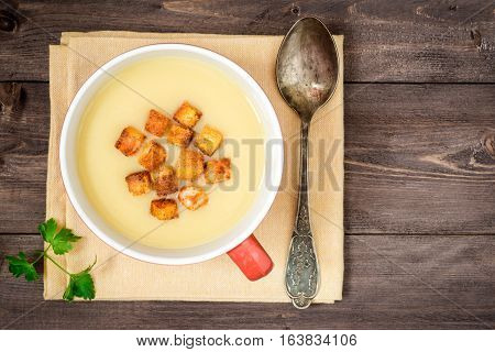 Homemade potato cream soup with croutons on wooden table. Top view.