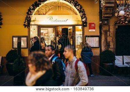 STRASBOURG FRANCE - DEC 20 2016: Woman entering French Restaurant through main festive gate during Christmas Holidays in French city of Strasbourg Maison Kammerzell