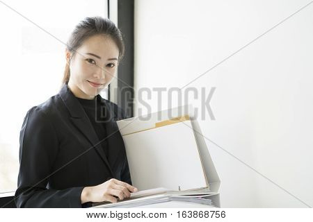 Asian Business woman holding document files beside a window