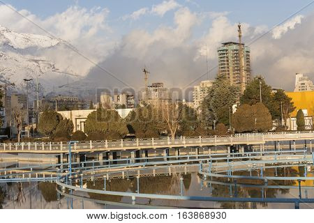 Tehran International Permanent Fairground Pool with Off Fountains Cityscape of Tehran and Alborz Mountains Covered by Snow at Background.