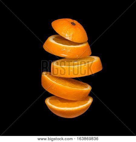 Flying orange. Sliced orange isolated on black background. Levity fruit floating in the air.