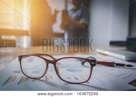 close up spectacles with ofountain pen over turnover graph paper it on wood desk in office.