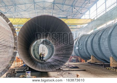 Great hall where workers welding rounded steel pipes.
