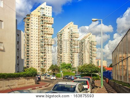 Rishon LeZion Israel-May 27 2016: Three multi-story modern residential buildings are flooded bright sunlight at Kheil ha-Avir Street on perfect sky background. There are some parked cars in front of it. Wide shot is taken from Heil HaShiryon street