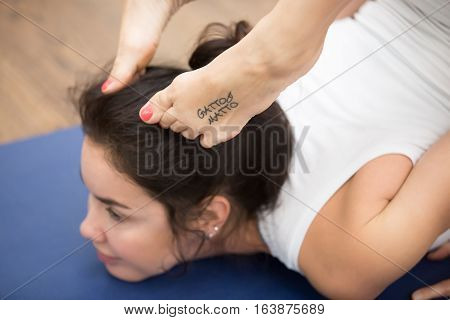 Portrait of beautiful young woman with tattoo on her foot meaning Wild kitty working out in fitness center, doing yoga or pilates exercise. Cheststand with backbend. Close up