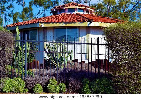 Yard with drought tolerant landscaping including chaparral plants and cacti taken beside a Spanish style house