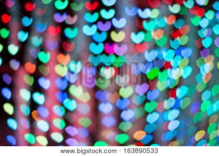 Defocused lights background. Heart bokeh. Bright colorful heart bokeh background. Multicolored blurry hearts on a black background.