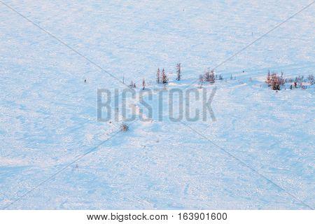 Aerial view above the snow covered tundra in time of short winter day.