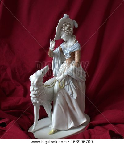 Porcelain figurine lady with dog Against the background of red velvet