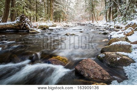 Winter river in the forest with river flowing gently along large rocks