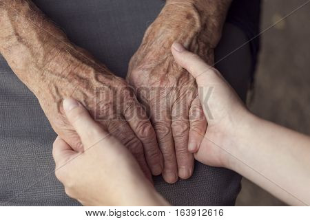 Old and young person holding hands. Elderly care and respect selective focus