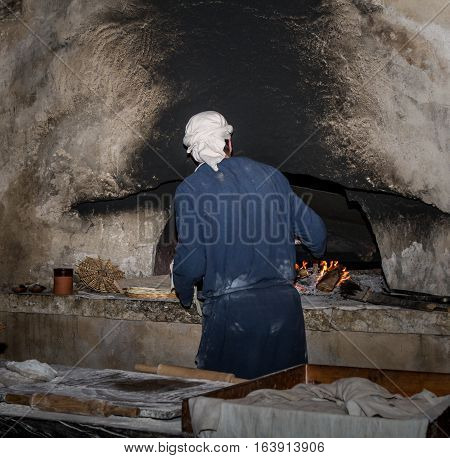 Man dressed in period clothes bakes bread in Nazareth Village Israel