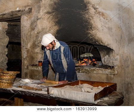 NAZARETH ISRAEL - DECEMBER 16: Man dressed in period clothes rolls the dough with rolling pin in Nazareth Village Israel on December 16 2016