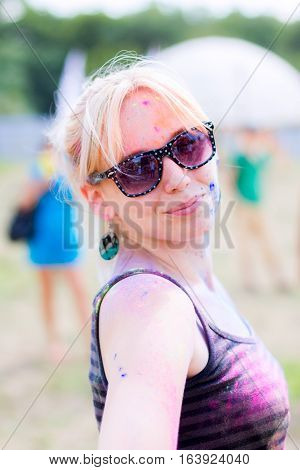 Portait of girl stained with colorful powder smiling during Holifest