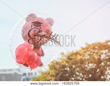 Red teddy bear in transparent balloon with congratulation text for graduate.