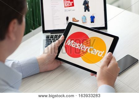 Alushta Russia - September 3 2016: Man holding a iPad Pro with payment system service MasterCard on the screen. iPad Pro was created and developed by the Apple inc.