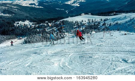 Several skiers go down the snowy slopes in the ski resort the view from the mountains