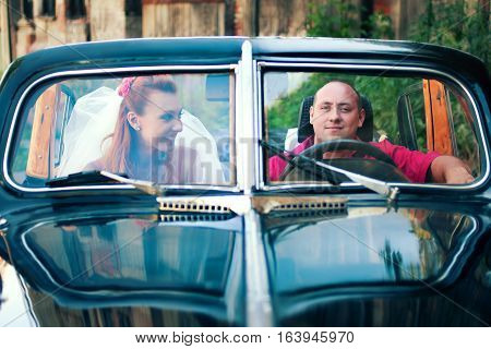 bride and groom in a retro car outdoor