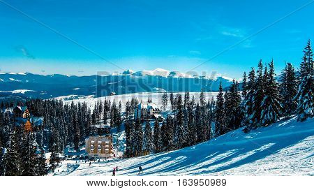 View from the high to the ski resort which attracts skiers on the ski slopes the snow-capped mountain peaks a village in winter mountains