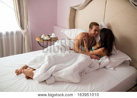 Caucasian couple in bedroom. Man smiling to lady. Time spent together is priceless.
