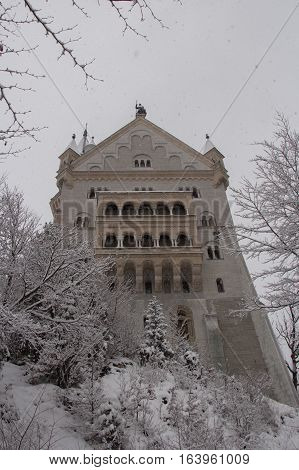 Fussen Germany - December 26 2014: close up view of Neuschwanstein Castle in winter time between trees on December 26 2014 near Fussen Germany.