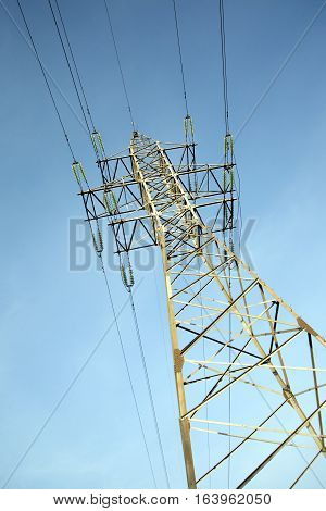 High-voltage power line grey metal prop with many wires vertical view over clear cloudless blue sky bottom-up view