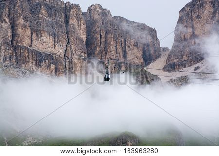 Sass Pordoi mountain massif hidden in clouds with cable car leading on top Dolomites Italy