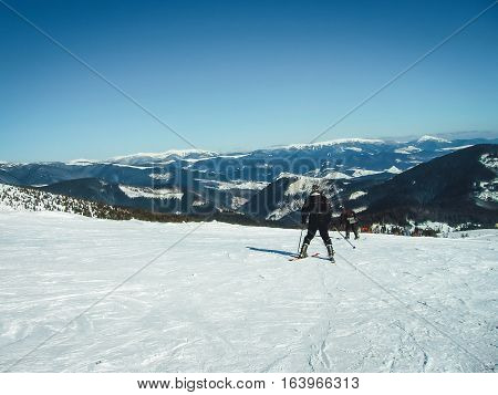 Skiers ride the mountain rear view, skier descends from the slopes, seen from behind