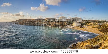 Ghajn Tuffieha Malta - Panoramic skyline view of Golden Bay Malta's most beautiful sandy beach at sunset with blue sky and clouds