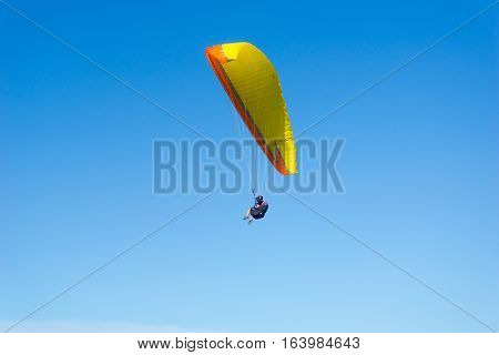 Mount Maunganui, New Zealand - December 21, 2016; Male para-glider enjoys the freedom flying in clear blue sky above the beach Mount Maunganui.